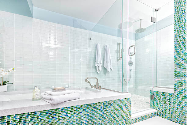 Subject: Contemporary residential home bathroom modern design featuring glass shower stall, bathtub, and glass wall tiles. Photographed in horizontal format with copy space.